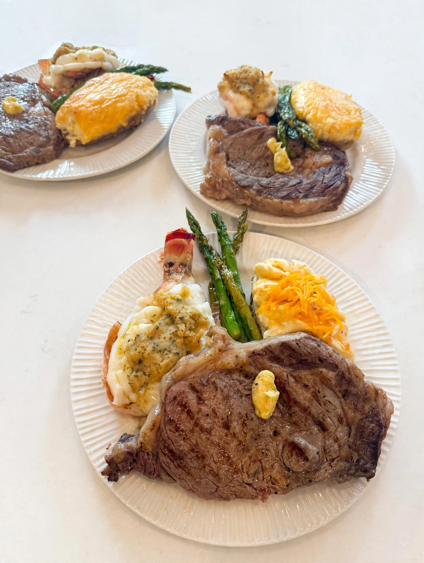 Plated steak dinners with asparagus, potatoes, and seafood prepared for a steakhouse pairing experience