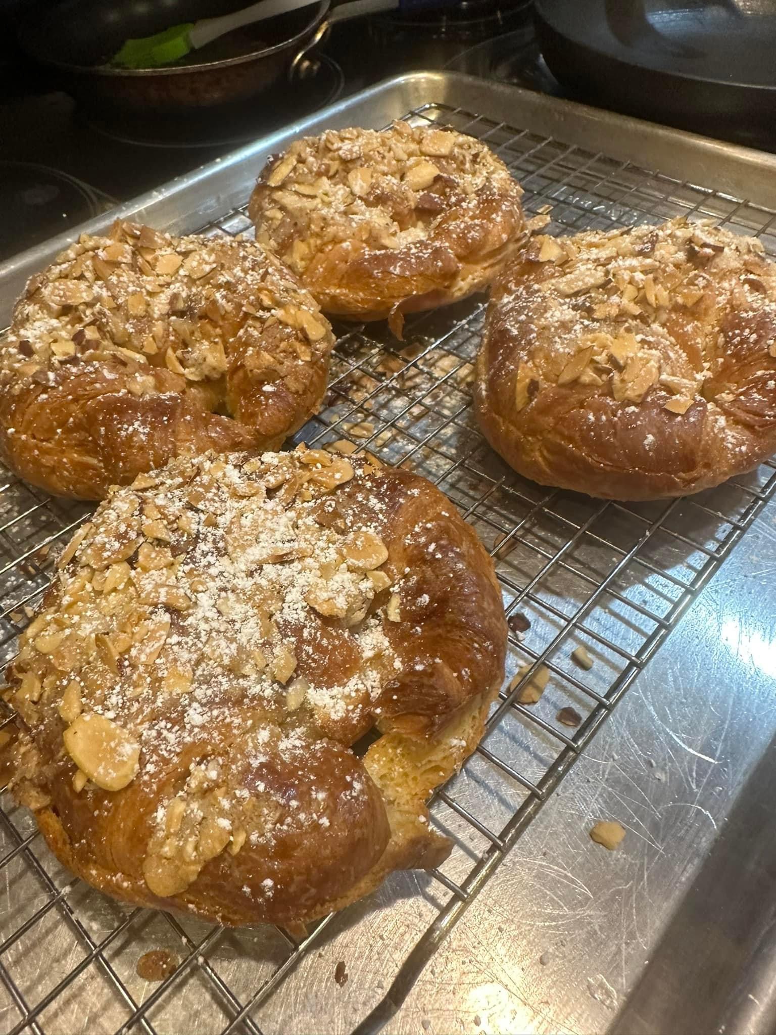 Fresh baked pastries topped with almonds and powdered sugar cooling on a rack