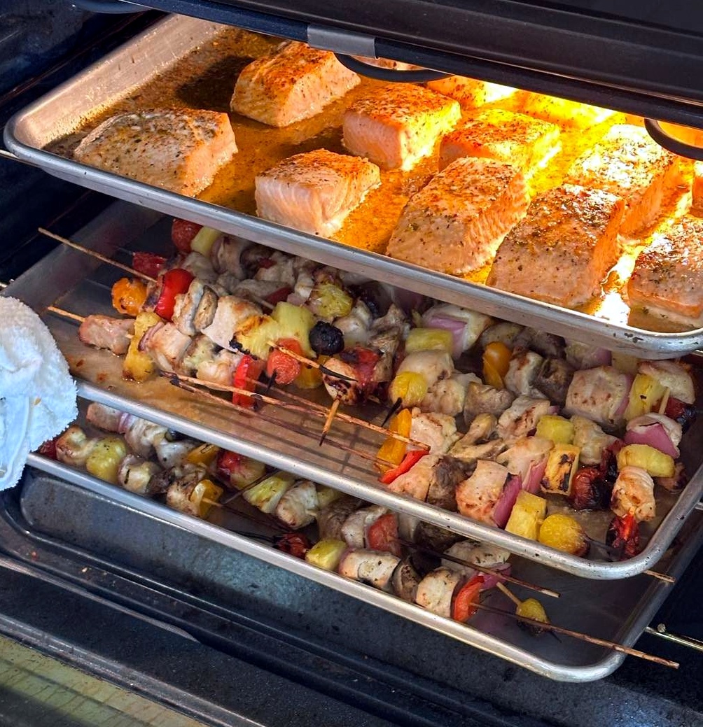 Prepared grilled meats and vegetables in catering trays for drop-off meal service