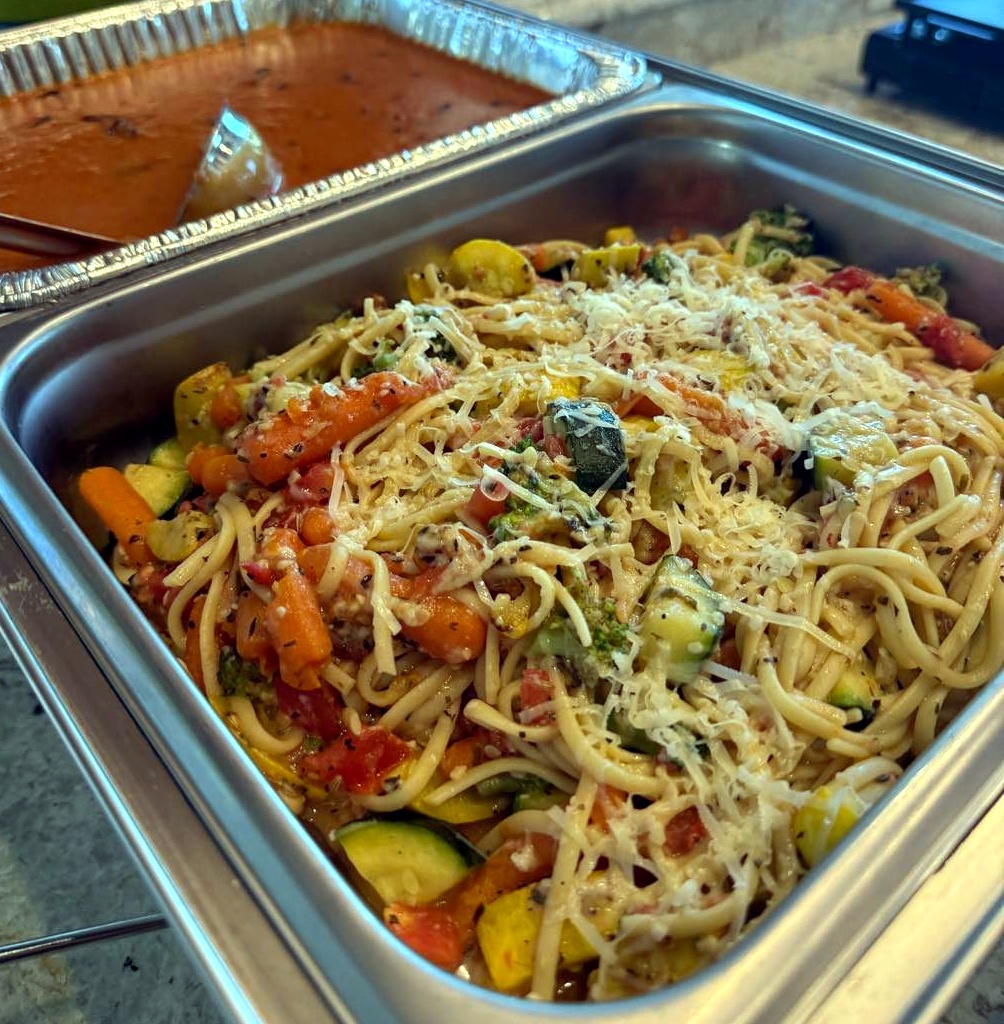 Prepared pasta with vegetables in a catering tray for drop-off meal service