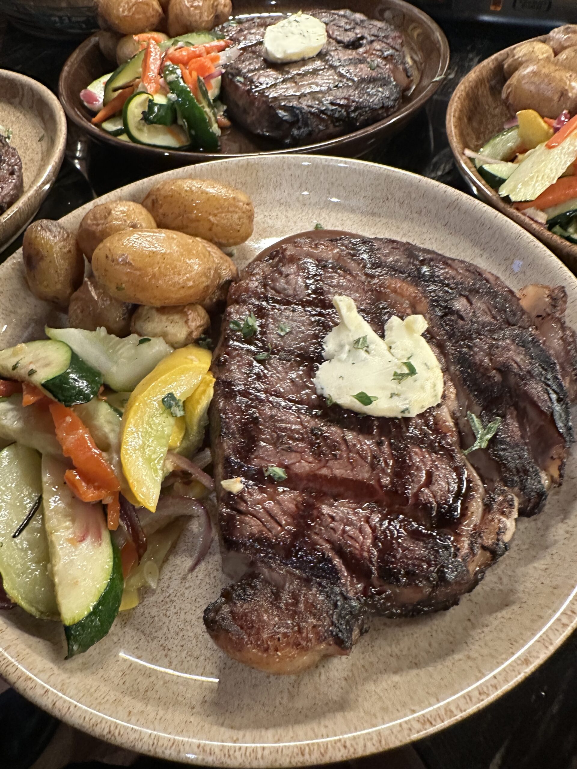 Plated steak entree with roasted potatoes and seasonal vegetables