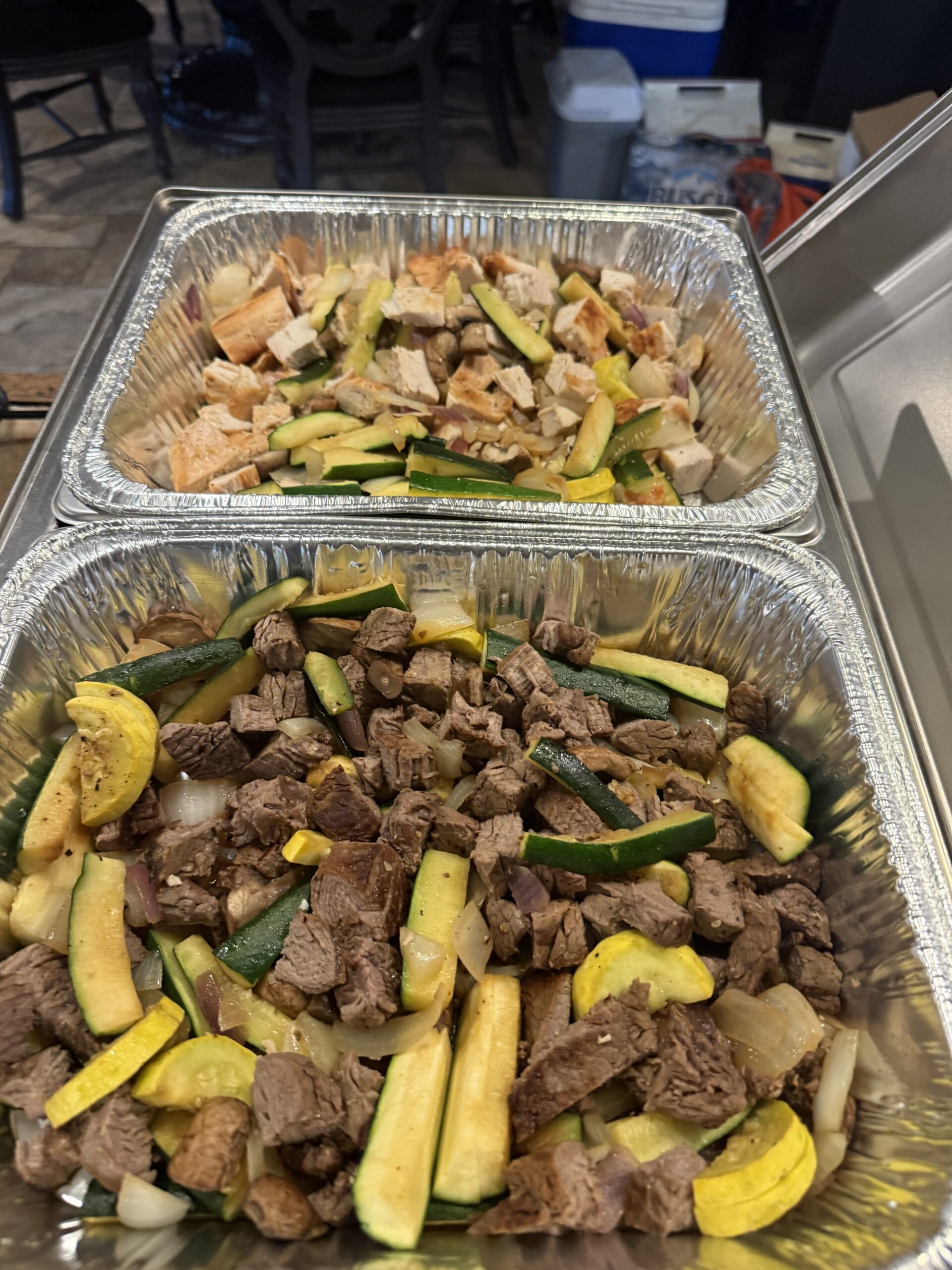 Prepared hibachi steak, chicken, and vegetables in catering trays