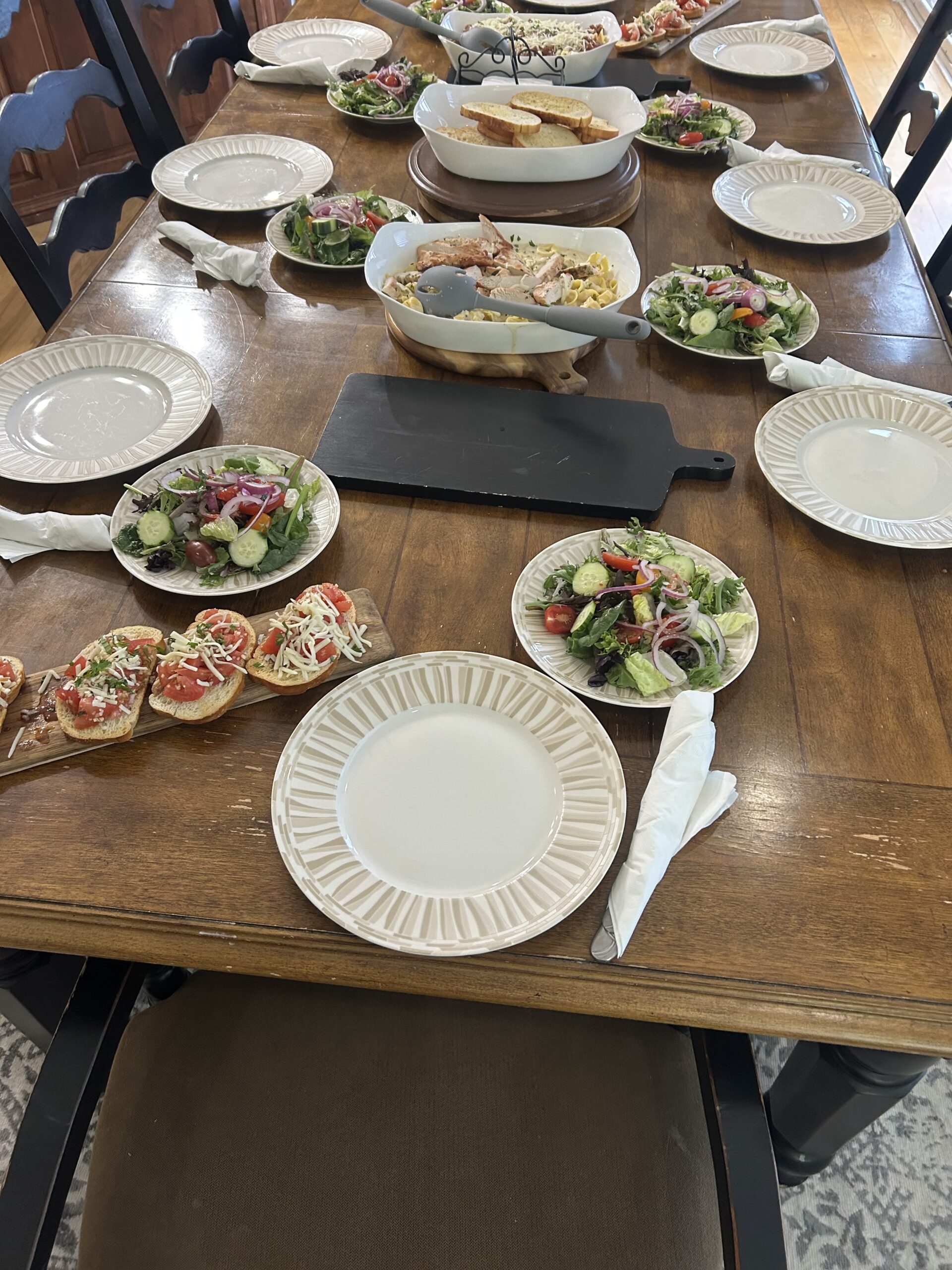 Catered four-course dinner table setup with salads, sandwiches, and plated service