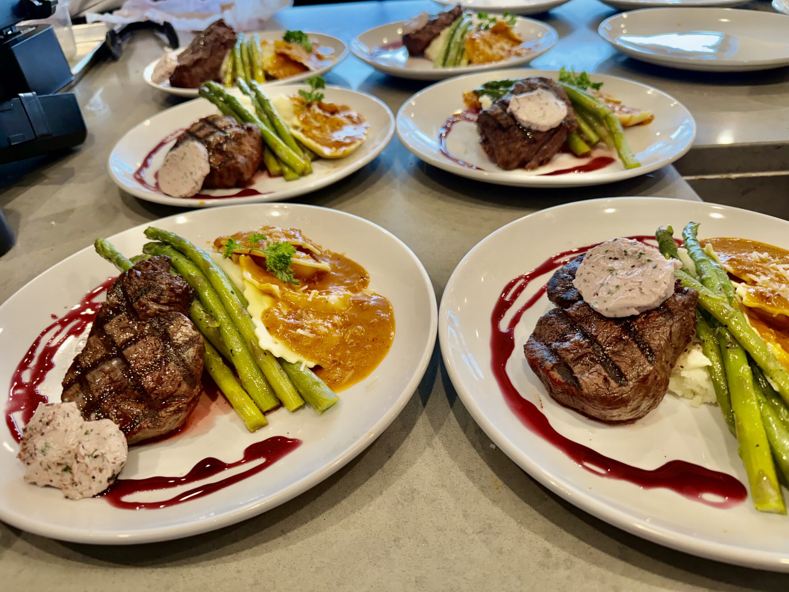 Four plated steak entrees with asparagus and sauce prepared for a private chef vacation home dining experience