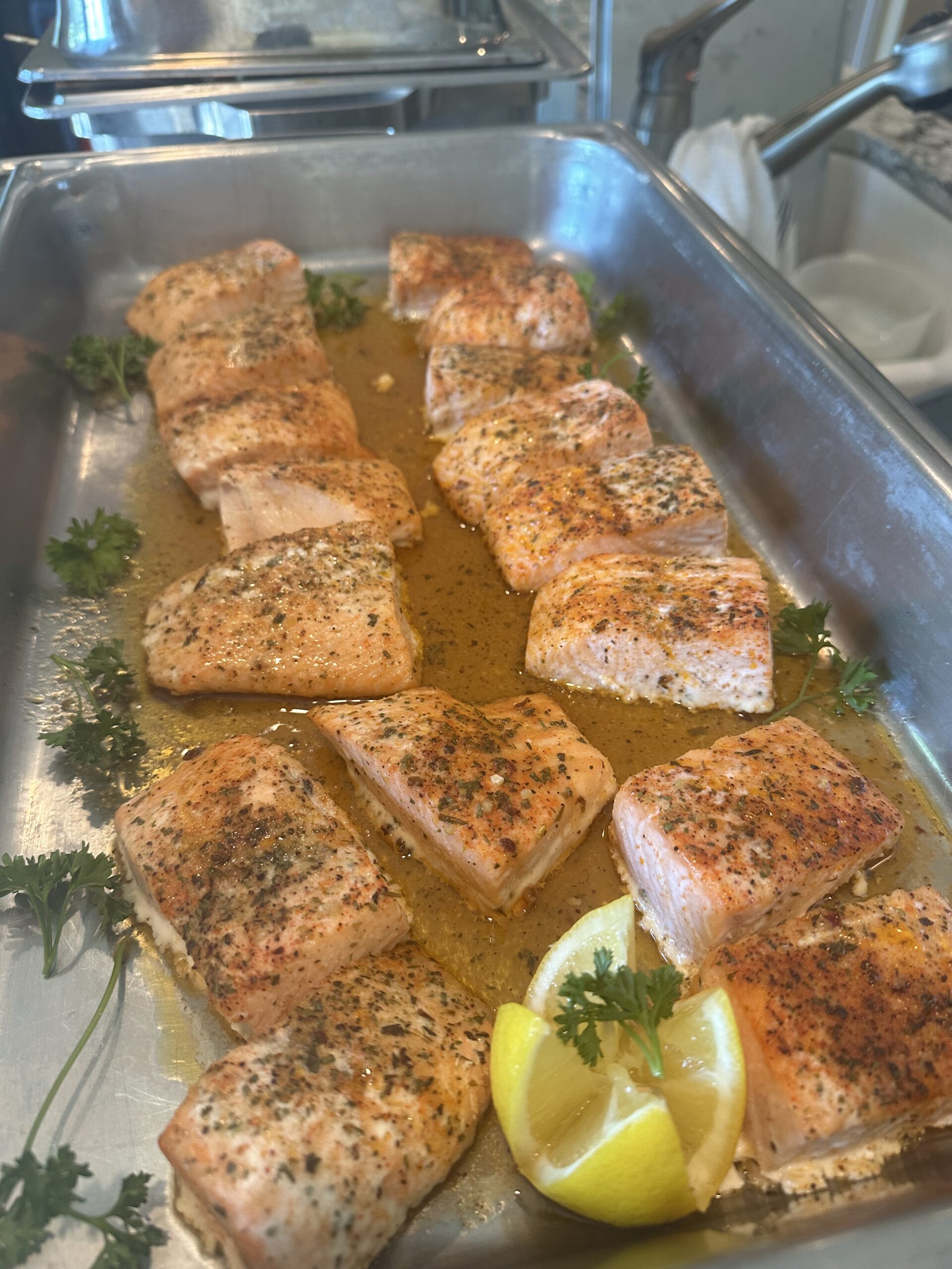 Seasoned salmon portions with lemon wedges prepared for a wedding or special event menu